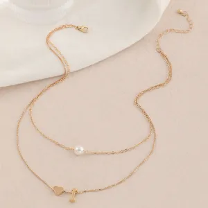 Exquisites zweilagiges Goldhalsband Detailfoto mit Perlenanhänger, Herz und kleinen Anhängern.