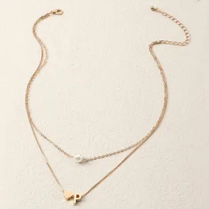 Nahaufnahme einer doppelreihigen Goldkette mit Perle, Herz und Anfangsbuchstabe P Anhänger.