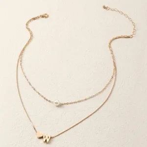 Detailaufnahme einer doppelten Goldkette mit Perle und Buchstaben W Anhaenger fuer Damen.