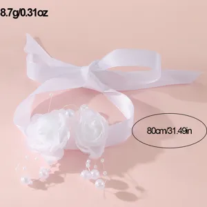 Close-up detail van witte lint polsbloem met parels en rozen voor elegante trouwaccessoire.