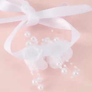 Detailopname van witte lint bruidsmeisje polsbloem met parels, mooie bruiloftsaccessoire.