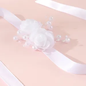Elegante witte polscorsage met rozen en parels op prachtig satijnen lint voor bruiloft.