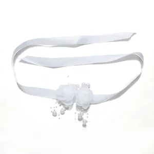 Close-up detail van witte bruids polsbloem met lint en parels, elegante huwelijksaccessoire.