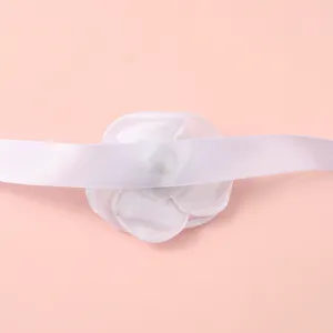 Gedetailleerde close-up van de elegante witte stoffen camelliabloem armband met satijnlint.