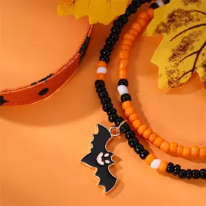 Dettaglio braccialetto di perline Halloween con ciondolo pipistrello e cinturino in pelle.