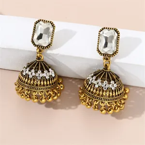 Détail en gros plan de boucles d'oreilles jhumka dorées de style indien avec zircon transparent.
