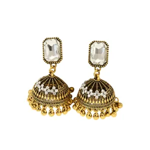 Gros plan sur des boucles d'oreilles jhumka en or style ethnique indien avec des cristaux de strass.