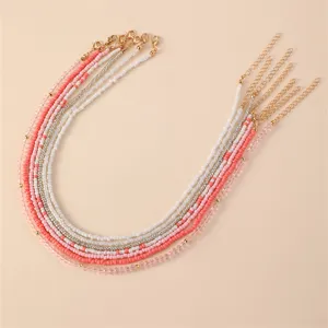 Bohemian layered beaded necklace set featuring pink white and crystal beads with gold chains.