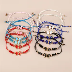 Detailansicht bunter geflochtener Armbänder mit Emaille-Schmetterlingsanhängern und Perlen.