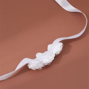 Dettaglio nastro di fiore in tessuto bianco, delicato bracciale da sposa e accessorio.