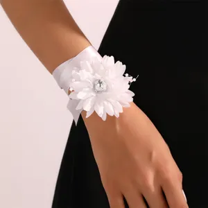 Fiore da polso in tessuto bianco con strass e perle, elegante gioiello da sposa.