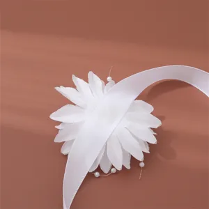 Primo piano dettaglio di corsage da polso elegante con fiore in tessuto bianco e perle.
