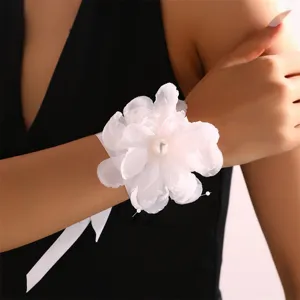 Dettaglio in primo piano del fiore da polso in tessuto bianco con perla, braccialetto nuziale.