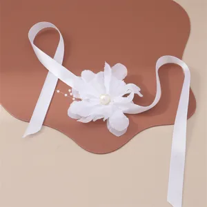 Dettaglio del bracciale con fiore in tessuto bianco con perla elegante e nastri lunghi.