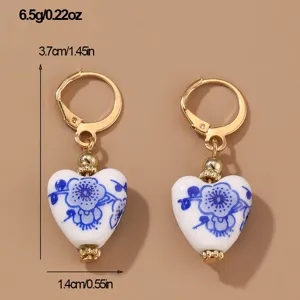Blue and white porcelain heart dangle earrings with gold tone lever back hooks for women detail.