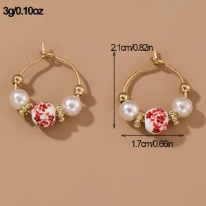 Detail view of vintage pearl hoop earrings with red floral ceramic bead and gold finish.