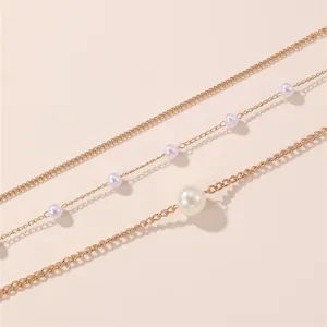 Nahaufnahme einer mehrlagigen goldenen Taillenkette mit eleganten Perlenornamenten für Damen.