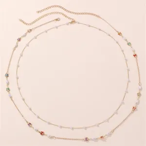 Nahaufnahme einer doppelten goldenen Taillenkette mit kleinen Perlen und bunten Schmetterlingen.