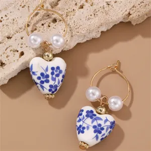Closeup detail of vintage blue white porcelain heart pearl hoop earrings, elegant chic design.