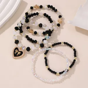 Detailansicht des charmanten Perlenarmband-Sets mit schwarz-weißen Perlen und Herz-Schleife.