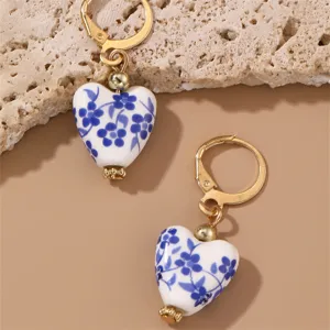 Close-up of blue and white porcelain heart earrings detail, stylish vintage ceramic jewelry design.