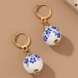 Close-up detail of vintage blue and white porcelain floral bead earrings with gold lever back.