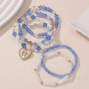 Blaues und weißes Perlenarmband-Set mit süßem Herz-Schleifen-Anhänger und goldenen Accessoires.
