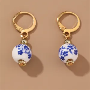 Vintage blue and white porcelain floral drop earrings with gold-toned leverback hooks.