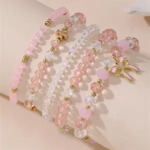 Schickes mehrteiliges rosafarbenes Perlenarmband-Set mit Kristallperlen und süßem Schleifenanhänger.