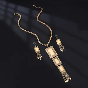 Detailansicht einer goldenen, hohlen Metallanhänger Halskette und passenden Ohrringen.