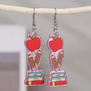 Gros plan détail enseignant rentrée résine pomme crayon livre paillettes boucles d'oreilles.