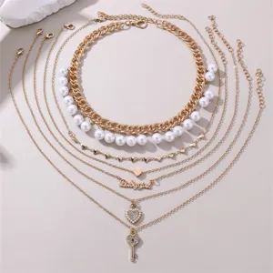 Mehrlagiges goldenes Halsketten-Set mit Perlen, Herzanhängern und Babygirl-Schriftzug.
