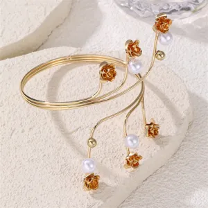 Primo piano dettagliato dell'elegante polsino dorato con rose delicate e perle bianche.