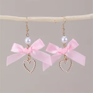 Nahaufnahme von rosa Schleife und Perlen Herz Ohrringen, eleganter Modeschmuck.