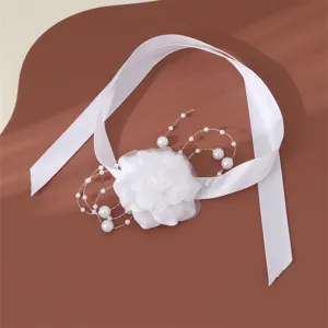 Primo piano dettagliato del braccialetto di fiori in tessuto bianco decorato con perle.