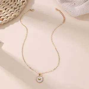 Detailaufnahme einer Goldkette mit weißem Muschelanhänger, elegantes modisches Accessoire.
