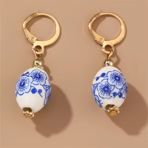 Close-up of vintage blue-and-white porcelain ceramic dangle earrings featuring gold-tone hardware.