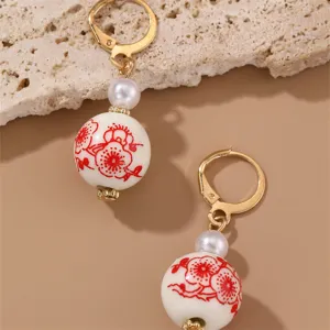 Close-up of vintage Chinese style drop earrings with red floral porcelain beads and pearls.