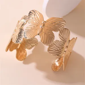 Detailansicht des breiten goldenen Armreifs mit hohlem Schmetterlingsmotiv für Damen.