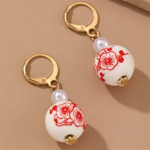 Chinese style red plum ceramic bead faux pearl dangle earrings with gold lever-back details.
