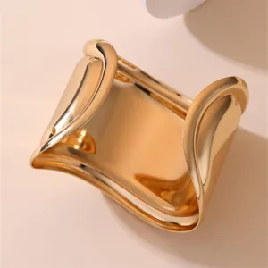 Nahaufnahme des breiten goldenen Armreifs aus Metall mit glatter polierter gewölbter Oberfläche.