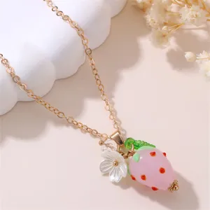 Close-up detail of sweet pink resin strawberry and white flower pendant necklace, elegant gold chain.