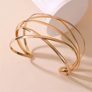 Nahaufnahme eines stilvollen goldenen Metall Mehrschicht Kreuz Armreifs mit glänzendem Finish.