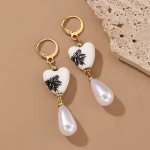 Retro gold dangle earrings with white ceramic heart beads, black plant patterns and pearl drops.