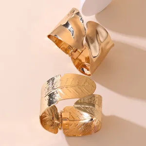 Goldene breite Armreif-Set mit unregelmässigen glatten und blattstrukturierten Stilen.