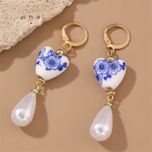Close-up detail of vintage Chinese style blue and white porcelain heart pearl earrings.