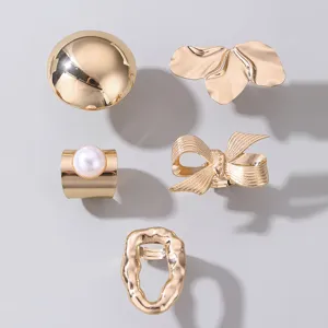 Set aus 5 minimalistischen goldenen Metallringen mit geometrischen und organischen Lavadesigns.