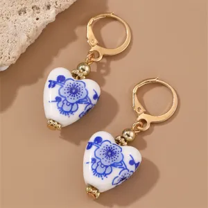 Close-up detail of vintage blue and white porcelain heart earrings with gold leverback closure.