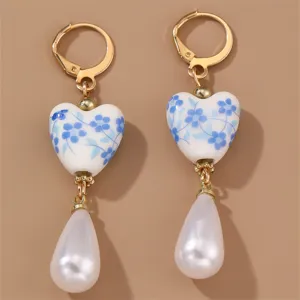 Close-up of elegant retro blue and white porcelain heart earrings with white teardrop pearls.