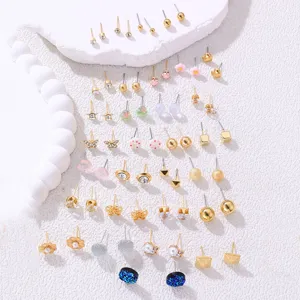 Detailaufnahme zarter Gold-Ohrstecker mit verschiedenen niedlichen geometrischen Perlen-Designs.